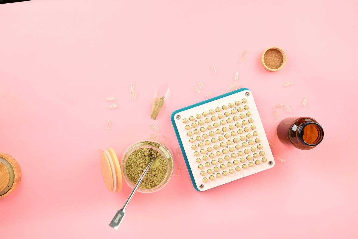 Red clover estrogen remedy capsules compared to raw dried flowers on wooden table
